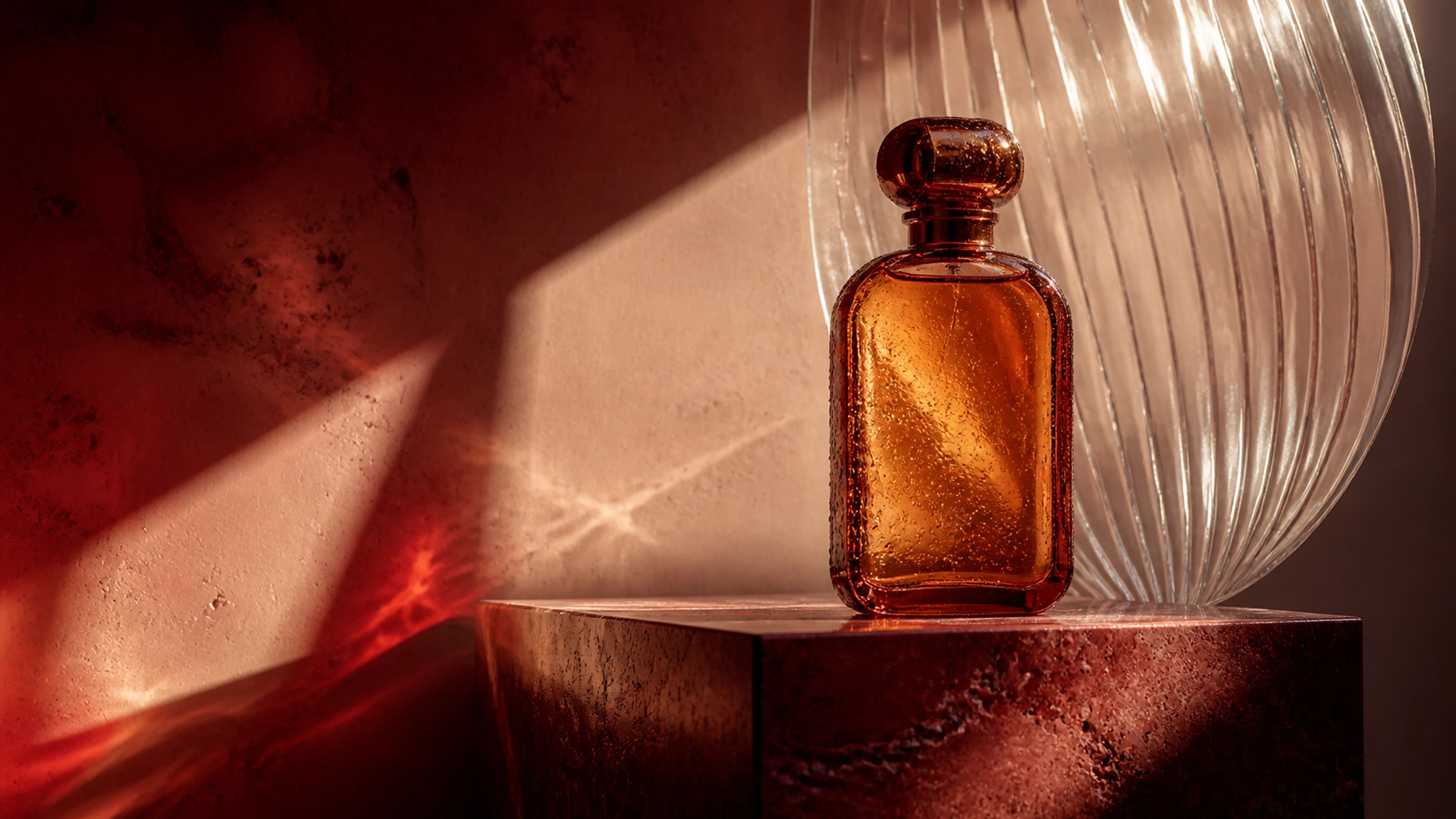 A sculptural amber perfume bottle on red travertine in warm directional sunlight